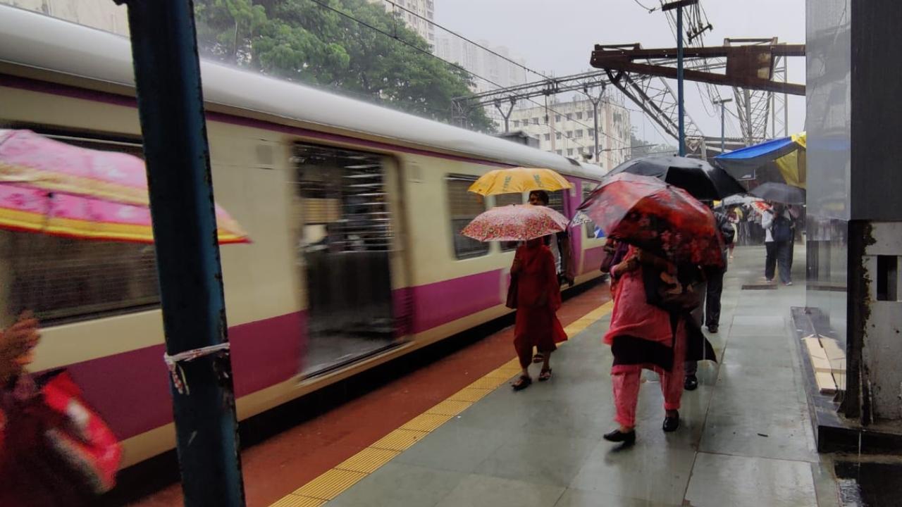 Passengers have to use umbrellas to avoid getting drenched at Byculla railway station where there is no roof. Pic/Sameer Markande